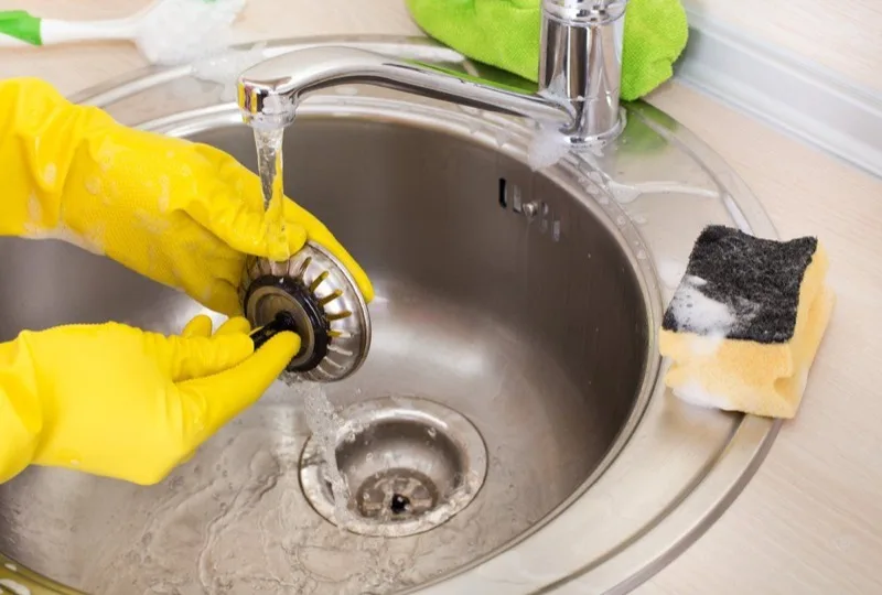 Technician clearing a clogged kitchen sink drain